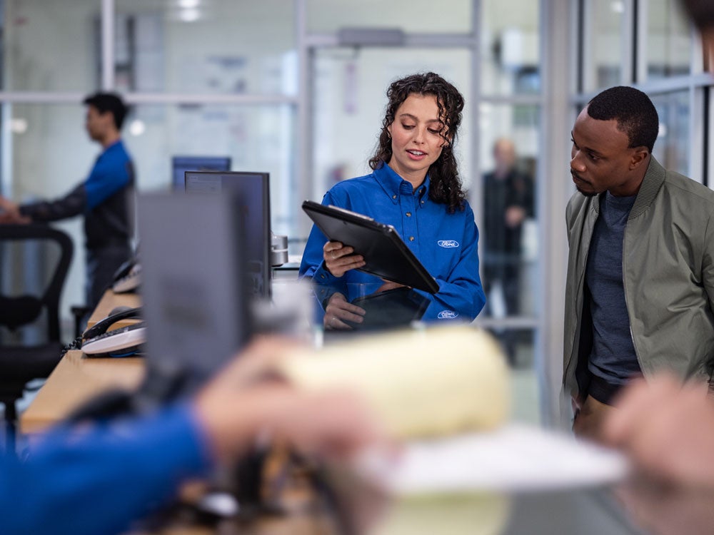 A Ford employee showing a customer information on a tablet.